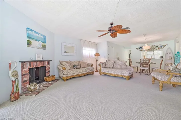 Carpeted living room featuring a fireplace, a textured ceiling, and ceiling fan