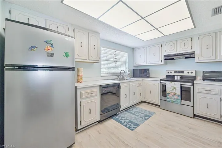 Kitchen featuring black appliances, sink, a textured ceiling, light wood-type flooring, and white cabinetry