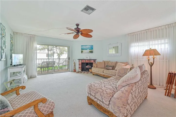 Living room featuring a brick fireplace, light colored carpet, and ceiling fan
