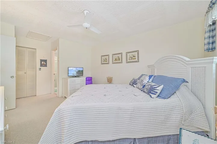 Bedroom featuring light carpet, a closet, a textured ceiling, and ceiling fan
