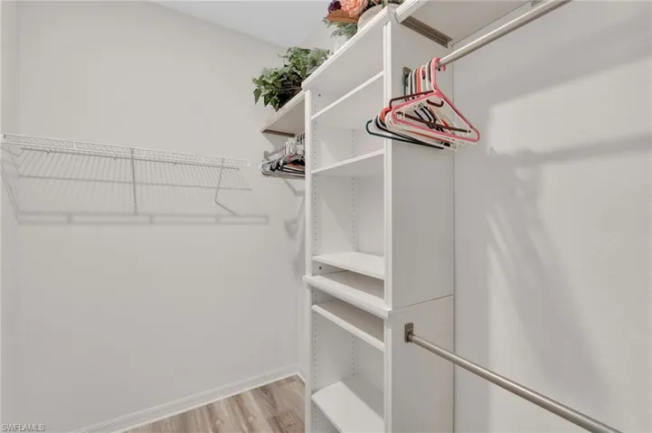 Bedroom featuring crown molding, a walk in closet, light wood-type flooring, and ceiling fan