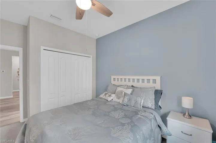 Carpeted bedroom featuring ceiling fan and a closet