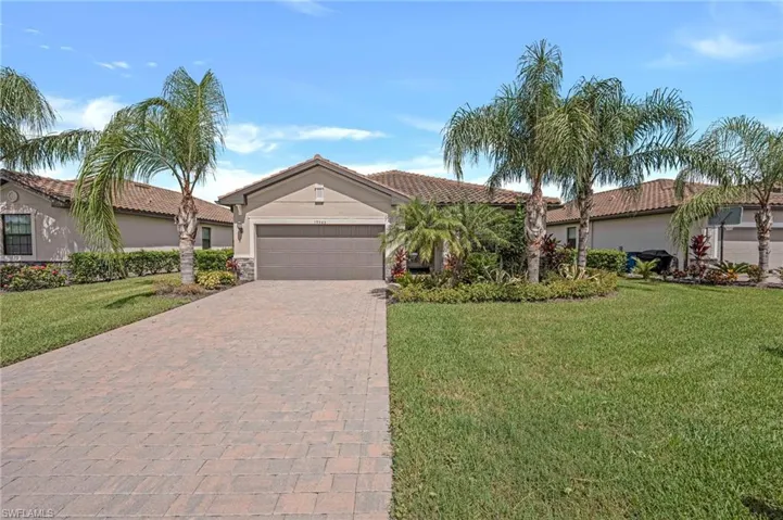 View of front of house with an attached garage, decorative driveway, a front yard, and stucco siding