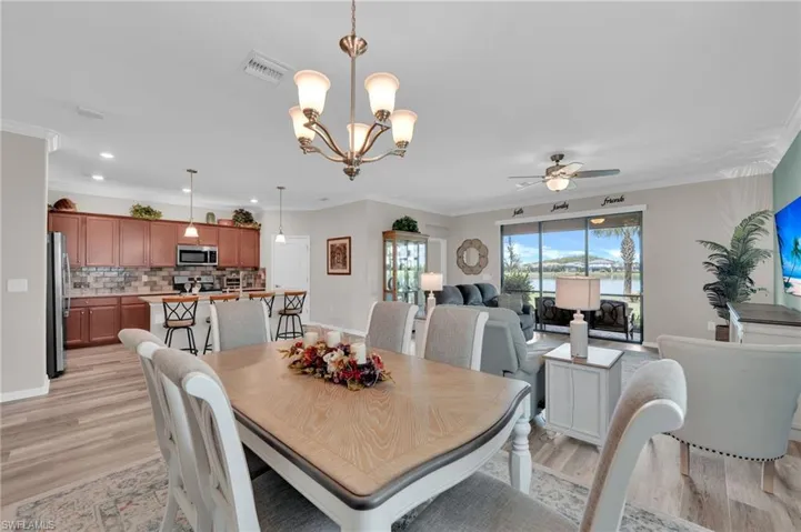 Dining space featuring crown molding, light wood-style floors, ceiling fan, and a chandelier