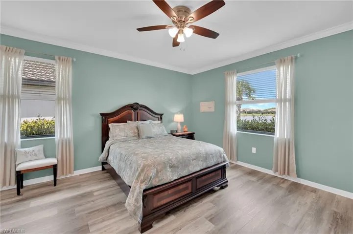 Bedroom featuring ornamental molding, light wood-type flooring, and ceiling fan