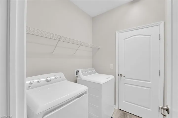 Laundry area with light wood-type flooring and washing machine and clothes dryer