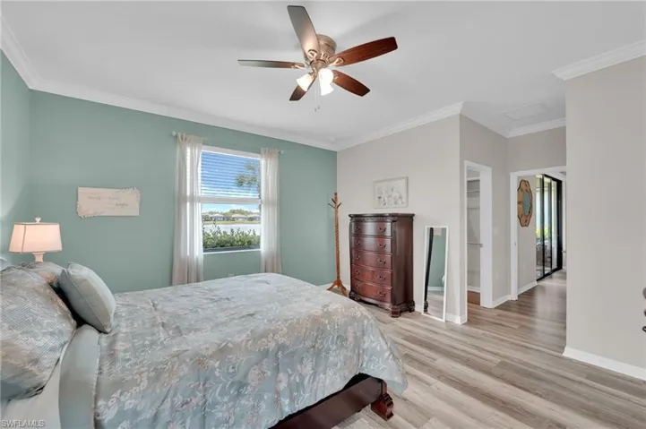 Bedroom featuring crown molding, a walk in closet, light wood-type flooring, and ceiling fan