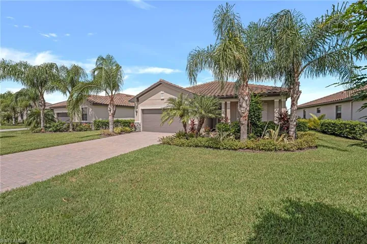 Mediterranean / spanish house with a front lawn, stucco siding, an attached garage, driveway, and a tiled roof