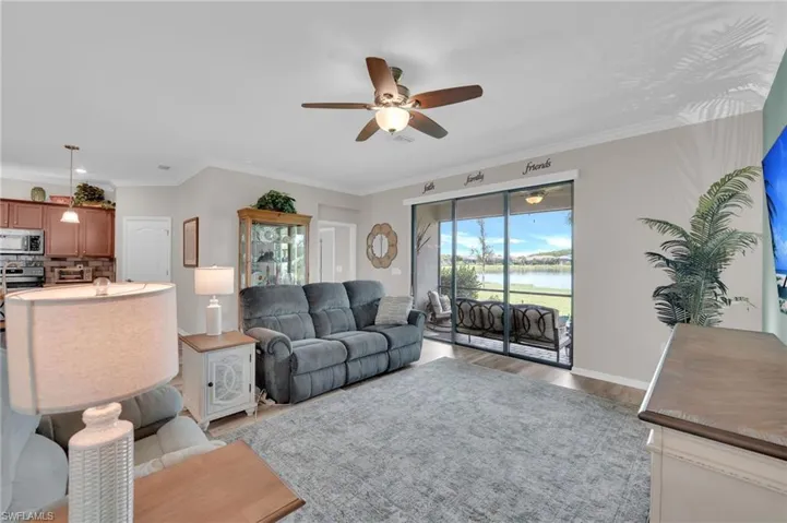 Living room featuring a water view, ornamental molding, a ceiling fan, and light wood-style floors