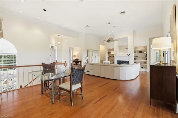 Dining room featuring light wood-style floors, crown molding, a fireplace, and a ceiling fan