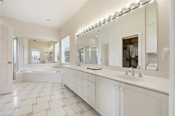 Full bathroom with a garden tub, double vanity, a shower stall, and a walk in closet