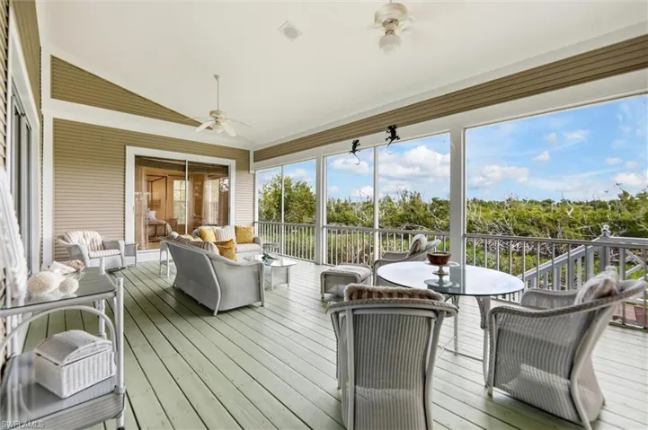 Sunroom with a ceiling fan, lofted ceiling, an outdoor living / dining area, and a wooden deck
