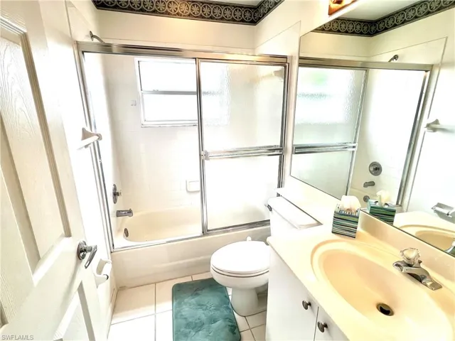 Full bathroom with vanity, toilet, tile patterned floors, and enclosed tub / shower combo