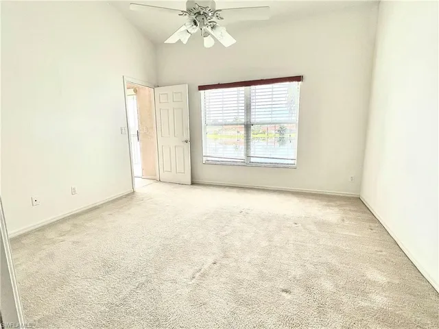 Carpeted spare room featuring high vaulted ceiling and ceiling fan
