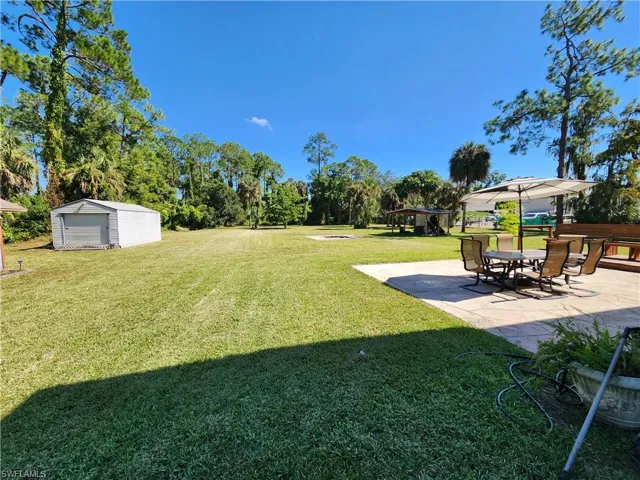 View of grassy yard with a patio area and an outdoor structure