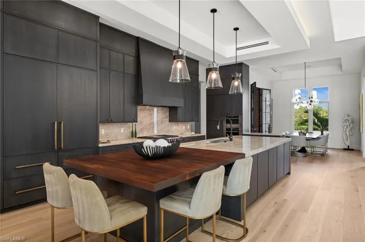Kitchen featuring a raised ceiling, a sink, a chandelier, decorative backsplash, and stainless steel gas stovetop