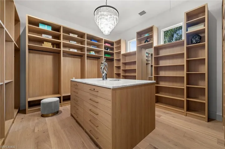Spacious Primary #1 closet with light wood-style floors and a chandelier