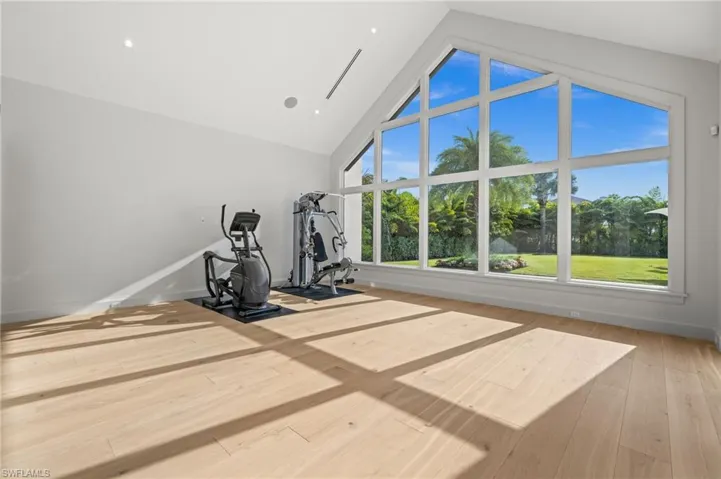 Exercise area featuring high vaulted ceiling, wood-type flooring, and baseboards