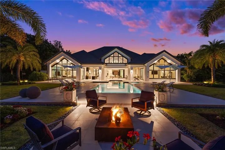 Rear view of property with a patio area, an outdoor pool, a lawn, stucco siding, and an outdoor living space with a fire pit