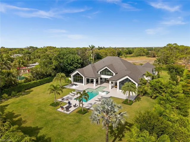 Aerial view of property and surrounding area with a pool and a tree filled landscape