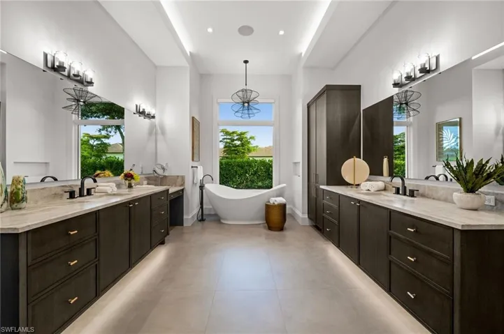 Full bathroom with healthy amount of natural light, a soaking tub, and two vanities