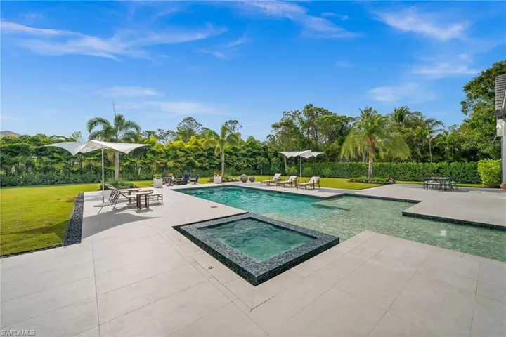 View of pool featuring a patio, a yard, and a pool with connected hot tub