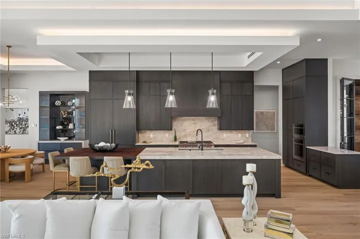 Kitchen with a raised ceiling, modern cabinets, light wood-type flooring, and backsplash