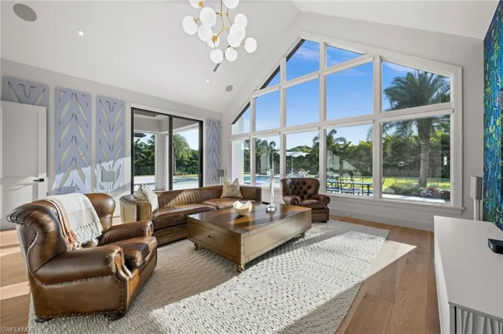 Media room featuring a chandelier, wood finished floors, high vaulted ceiling, and plenty of natural light