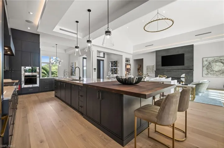 Kitchen featuring a chandelier, wood counters, a sink, a raised ceiling, and a spacious island
