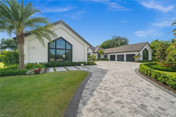 View of front facade with stucco siding, a front yard, decorative driveway, and a garage