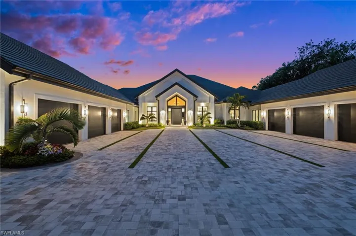 View of front of home with decorative driveway, a garage, and stucco siding