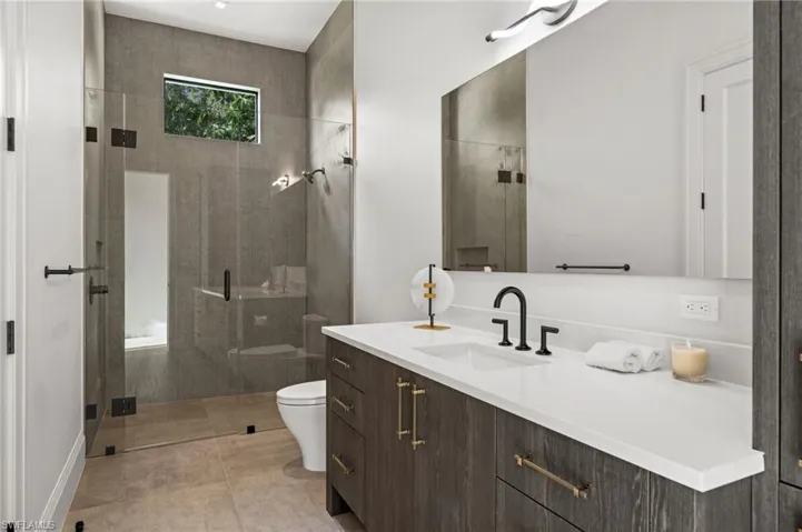 Bathroom with toilet, a stall shower, vanity, and tile patterned flooring