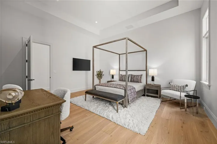 Bedroom with baseboards, light wood-style floors, and a tray ceiling