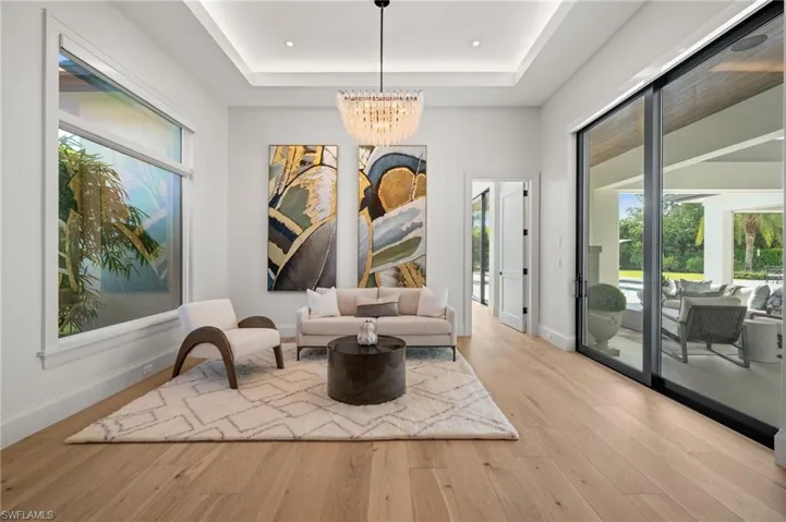 Primary Bedroom Sitting room with a chandelier, a raised ceiling, wood finished floors, and baseboards