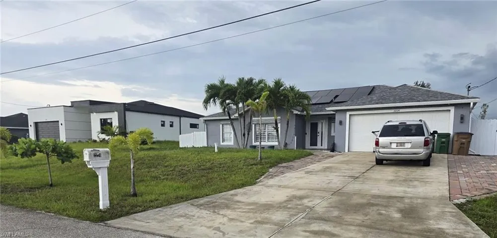 Single story home featuring stucco siding, solar panels, roof with shingles, concrete driveway, and a garage