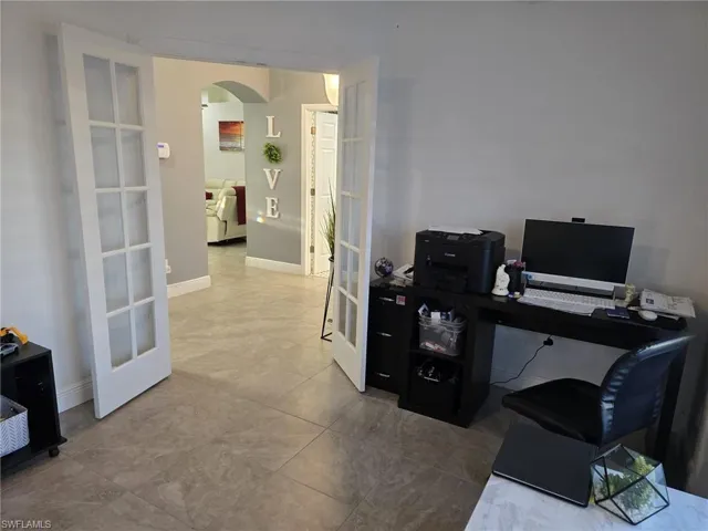 Office space featuring arched walkways, french doors, and light tile patterned flooring