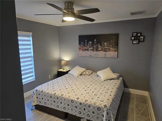 Bedroom with ornamental molding, a ceiling fan, and tile patterned floors
