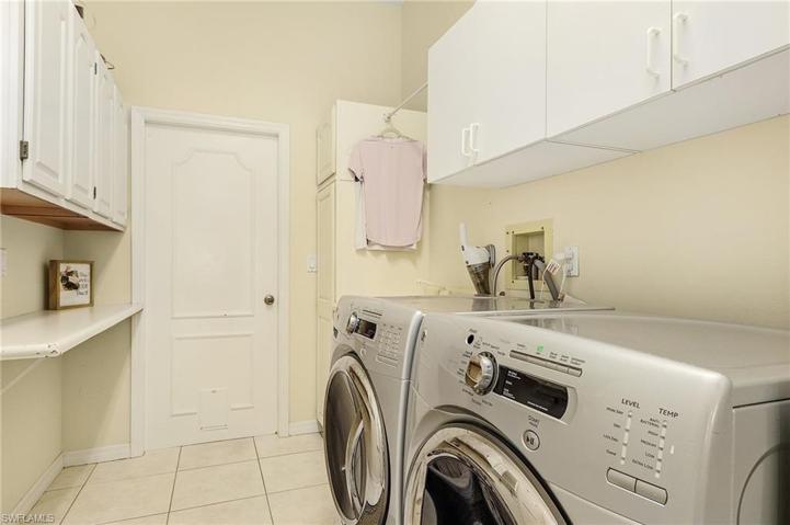 Large laundry area features newer washer and dryer, plenty of cabinet storage, built-in ironing board, tile floors, drying rod, folding table, pantry closet.