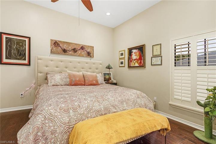 Guest bedroom with ceiling fan, wood floors, plantation shutters.