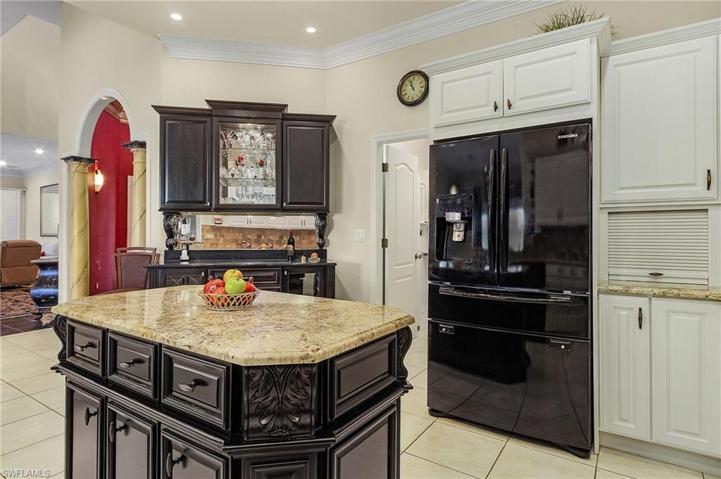 Spacious kitchen with prep island, bar cabinetry with wine storage, white cabinets, tile floors.