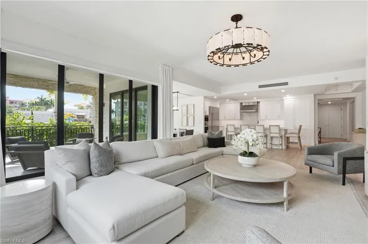 Open-concept living area with wood-finish flooring, a contemporary chandelier, and recessed lighting