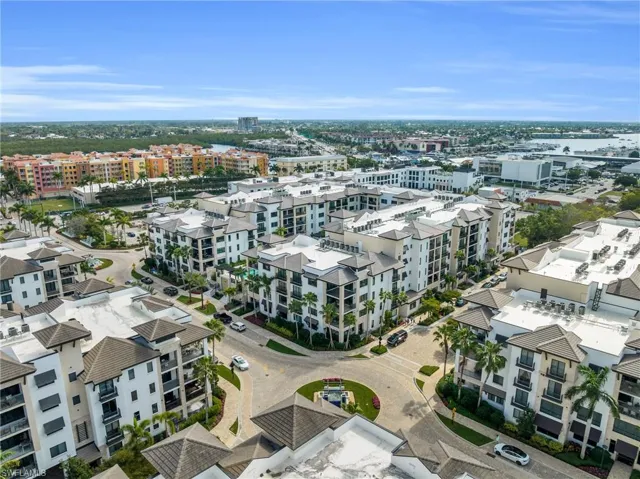 Mixed-use development featuring multi-story residential buildings, private balconies, a central roundabout, and lush landscaping