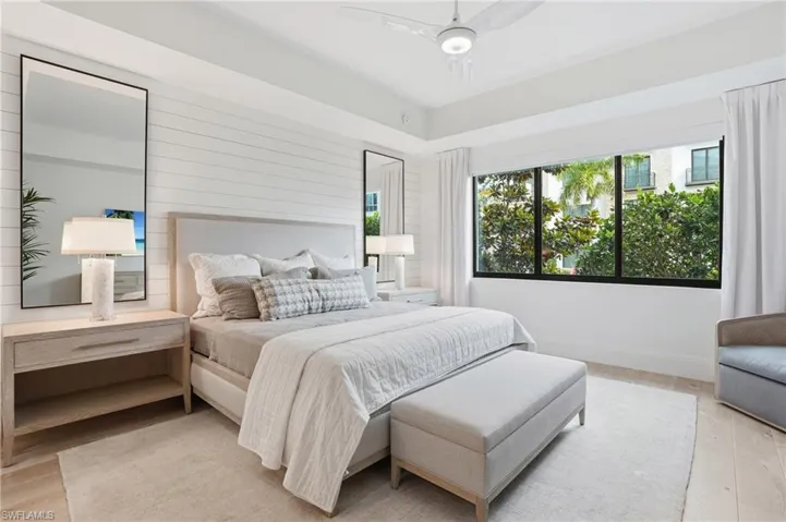 Shiplap accent wall, recessed lighting, ceiling fan, large windows, and wood-finish flooring