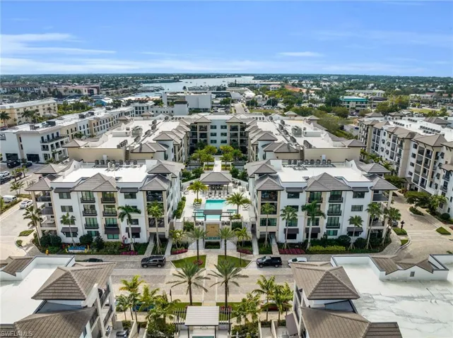 Multi-story residential complex featuring a central courtyard, an outdoor swimming pool, and structured landscaping with palm trees