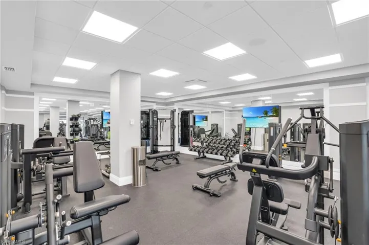 Fitness area featuring multiple exercise machines, mirrored walls, and recessed lighting