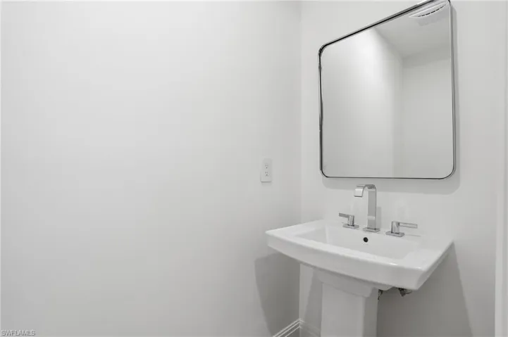 Pedestal sink with chrome fixtures and a rectangular mirror