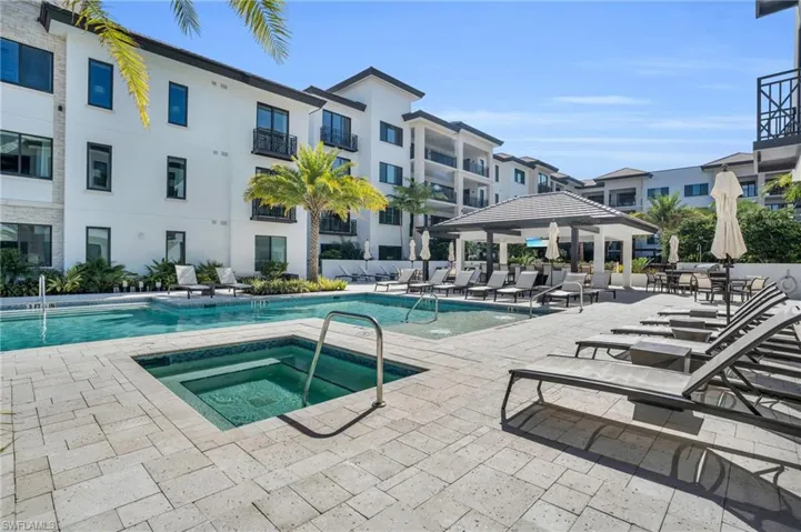 Resort-style pool area featuring an integrated spa, paver decking, and a covered cabana