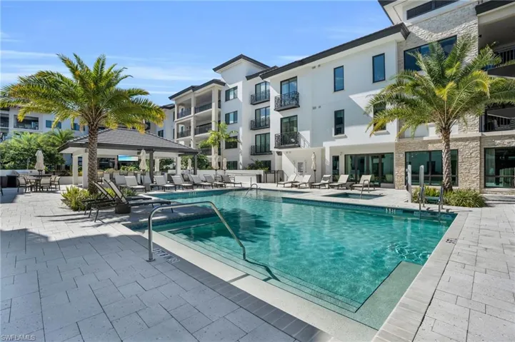 Resort-style swimming pool and spa with integrated steps, surrounded by a paver patio and a covered cabana