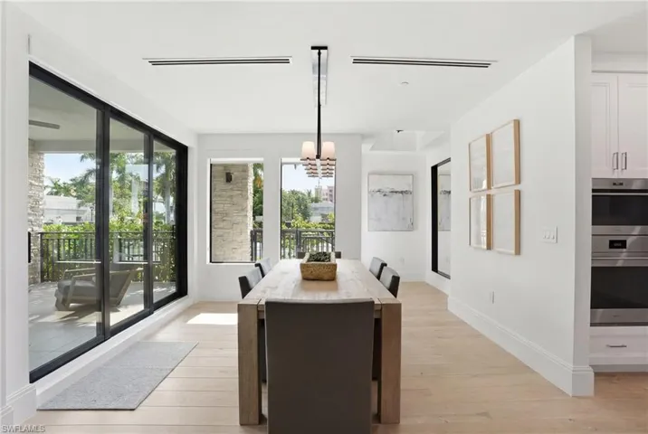 Wood-finish flooring, white cabinetry, integrated double ovens, and a built-in microwave
