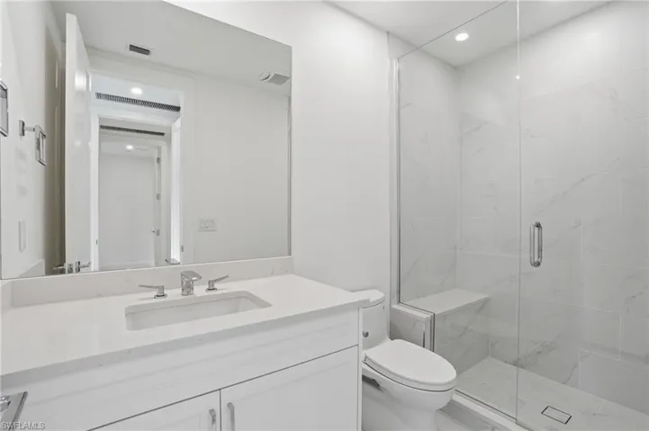 White vanity with an integrated sink, polished chrome faucet, and expansive mirror